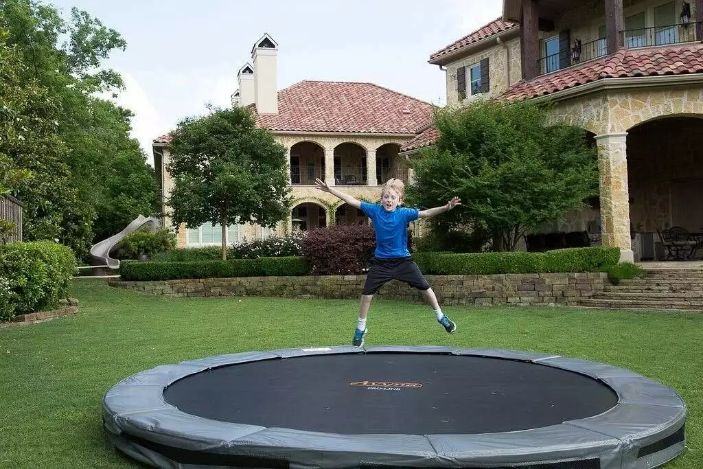How to choose an in-ground trampoline A child jumping on an inground trampoline